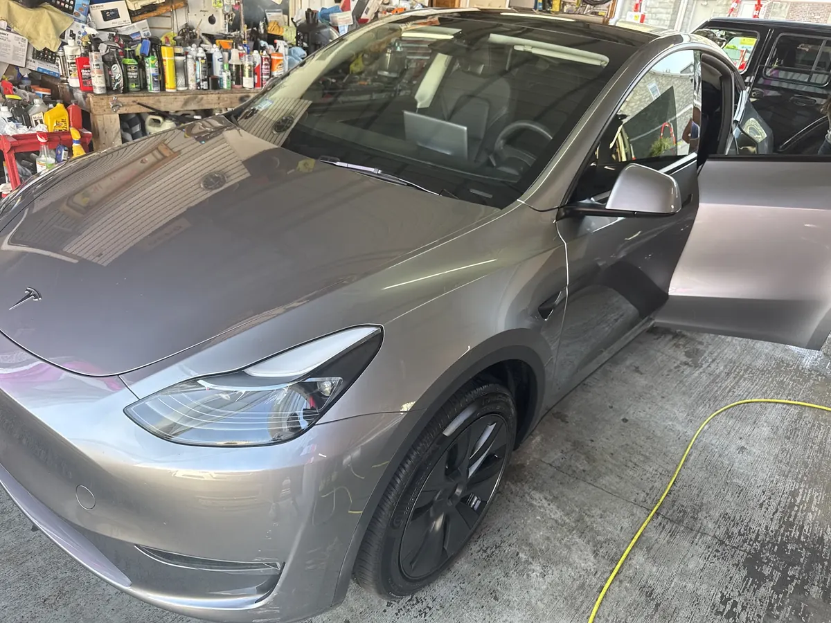 Silver Tesla Model Y with a door open in the detailing bay