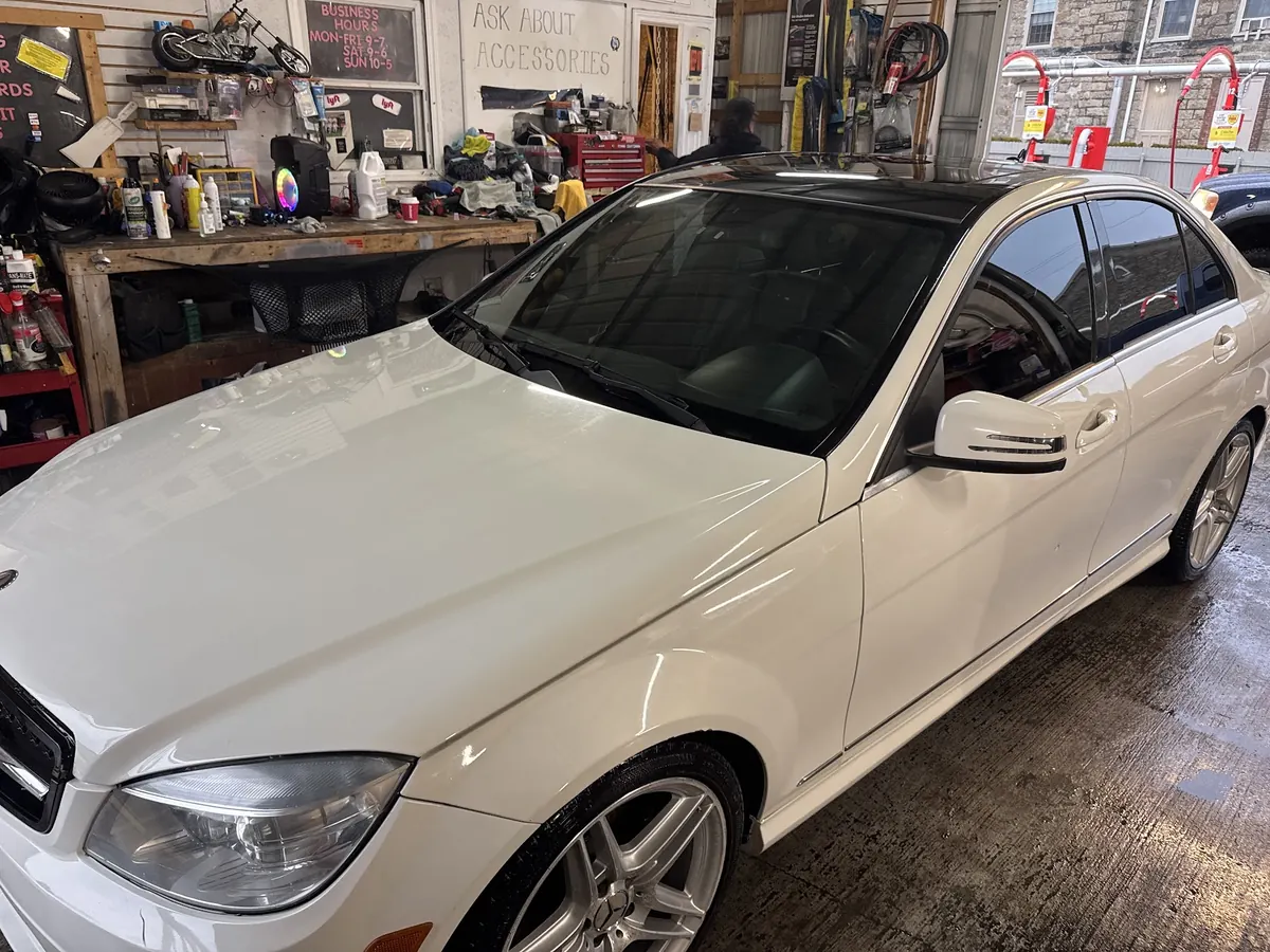 White Mercedes-Benz C-Class with dark tinted windows in the shop